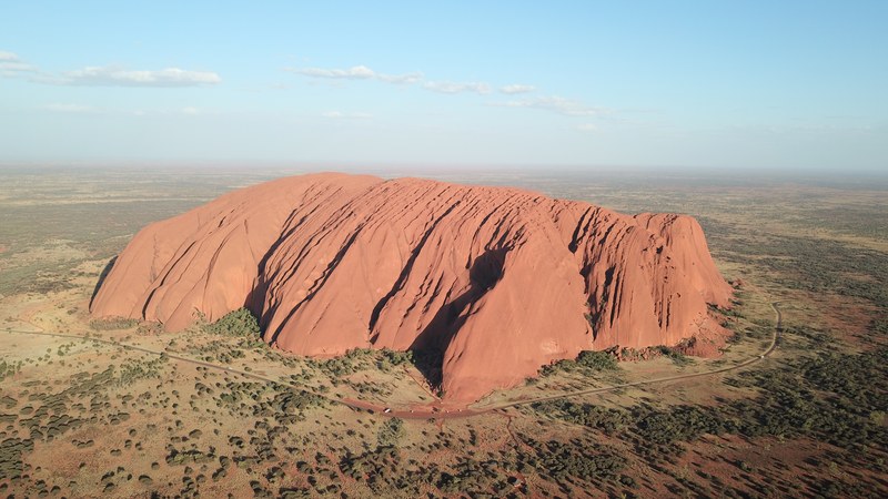 Uluru from the air at sunrise, the road circling the base of the monolith